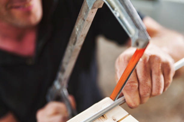 istock Carpenter using hacksaw for cutting metal rod in workshop 2165790493
