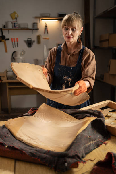 Timeless Restoration: Elderly Woman Expertly Disassembling Vintage Armchair in Workshop