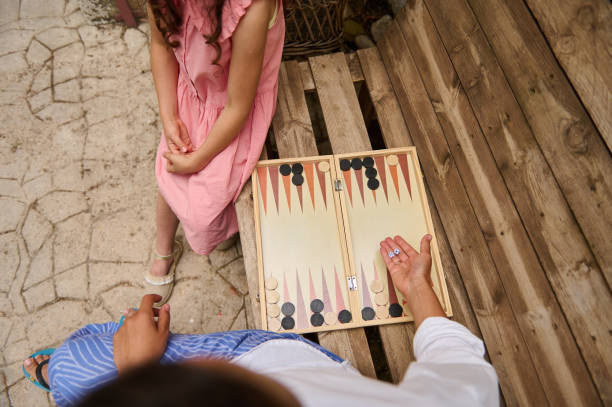 istock Two people playing backgammon on a wooden bench outdoors 2165795037