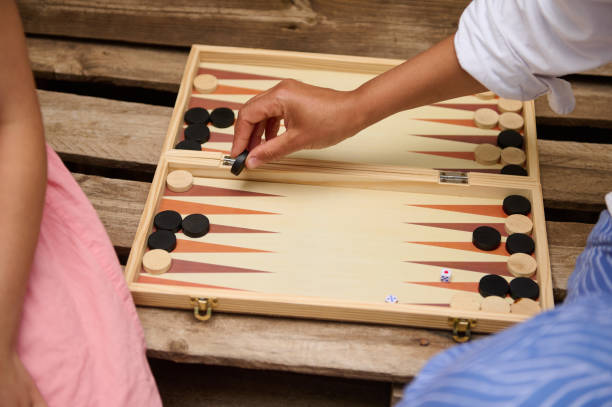 istock People playing backgammon on a wooden board outdoors, enjoying a friendly game 2165795106