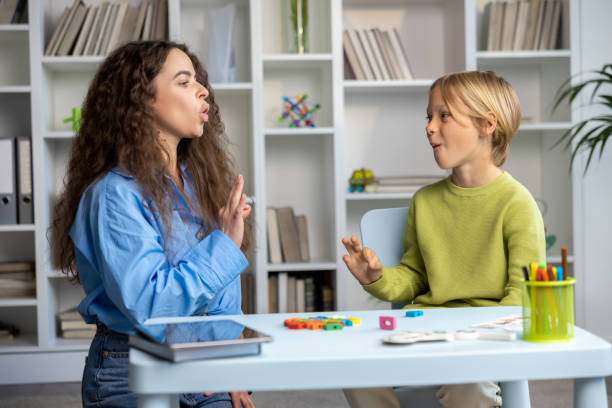 istock Blonde boy exercising with speech therapist and making efforts 2165795747