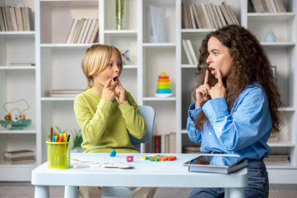 istock Blonde boy exercising with speech therapist and making efforts 2165795787