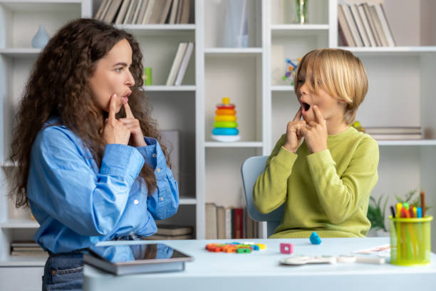 istock Blonde boy exercising with speech therapist and making efforts 2165795895