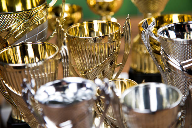 Closeup picrure of golden trophy. Soccer prize on grass soccer venue. Golden trophy with handles