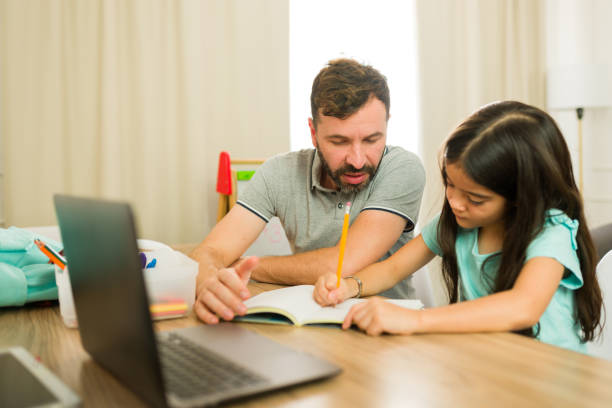 istock Father homeschooling her daughter and helping her solve a few math problems 2165799219