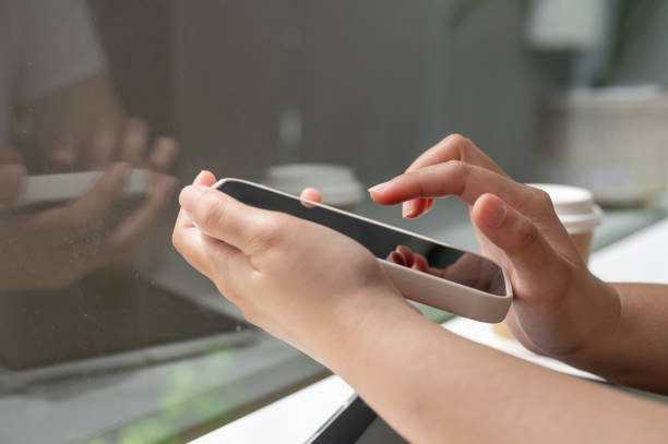 istock A close-up side view image of a woman using her smartphone while sitting in a coffee shop. 2165799582