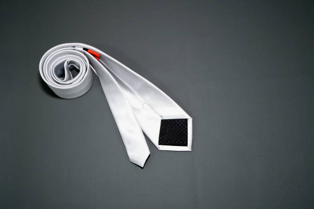 A white color polyester fabric necktie rolled on grey background close-up view single object, Father's day concept, no people