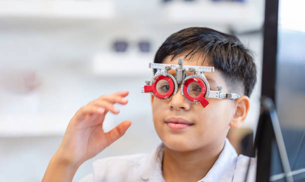 istock Boy doing eye test checking examination with optometrist in optics store, Indian kid boy choosing eyeglasses in optics store 2165802686