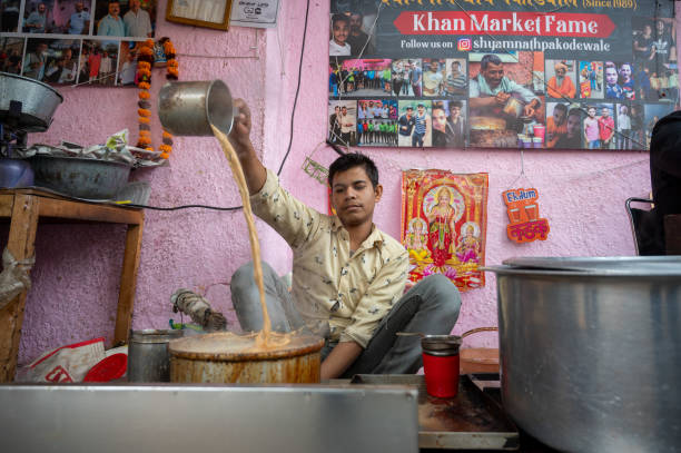 New Delhi, India-December 22,2023: Man making tea in a traditional street style at a roadside shop.