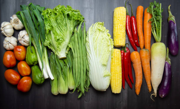 istock Fresh Mixed Raw Vegetables on Wooden Table – Corn, Tomatoes, Garlic, Lettuce, and More 2165810542