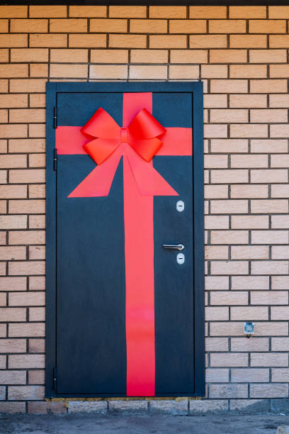 istock The charming red bow on the striking black door stands out against brickwork, creating a captivating feature in a balanced design. The door becomes a standout element in the setting 2165820461