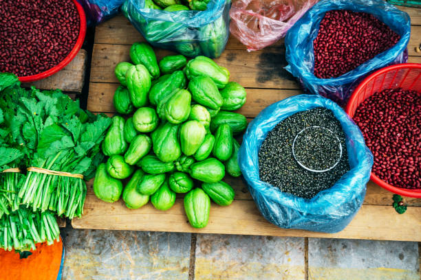 Top view of fresh vegetables and various beans displayed at a traditional Vietnamese market, showcasing vibrant and natural produce.