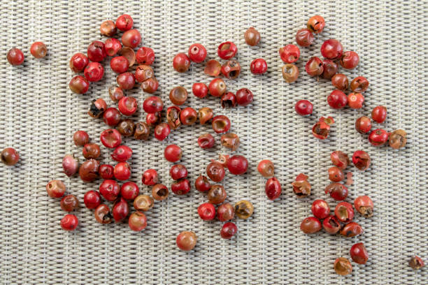 Red or pink peppercorns on grey textured cutting board background top view