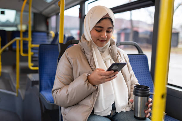 Young woman riding in a bus and using her phone