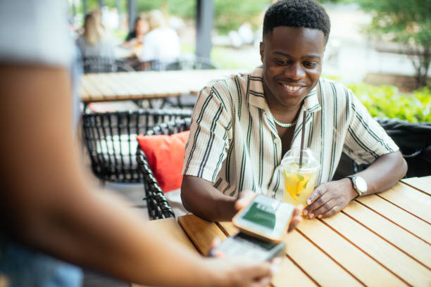 istock Young man paying with smartphone in a cafe 2165830251