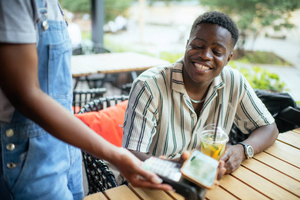 istock Young man paying with smartphone in a cafe 2165830259