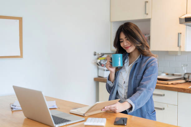 istock Young Woman Working Online from Home in Modern Kitchen with Laptop and Coffee Mug, Remote Work Concept 2165837986
