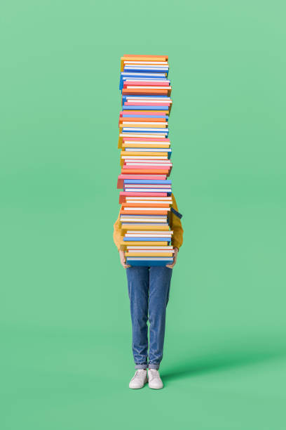 istock Woman Holding a Tall Stack of Books on Green Background 2165838643