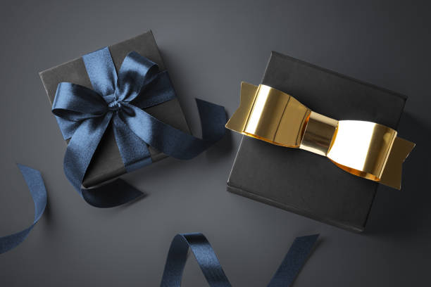 istock Black gift box with gold bow and blue ribbon on dark background 2165841188