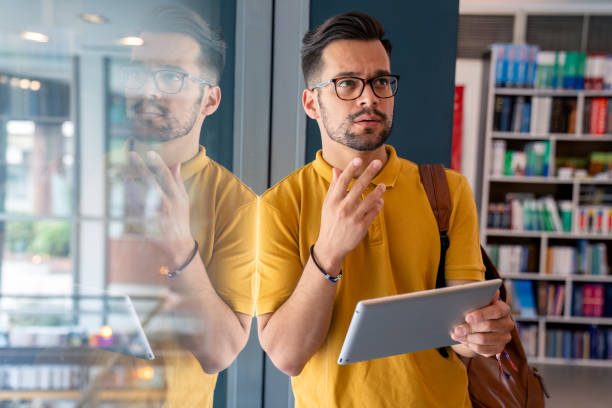 istock Focused Caucasian Male Student with Tablet at Library 2165842141