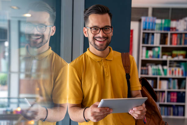 istock Smiling Caucasian Male Student with Tablet by Library Window 2165842308