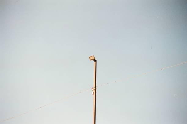 A lone street light stands tall against a vast clear sky, symbolizing urban simplicity and solitary illumination.