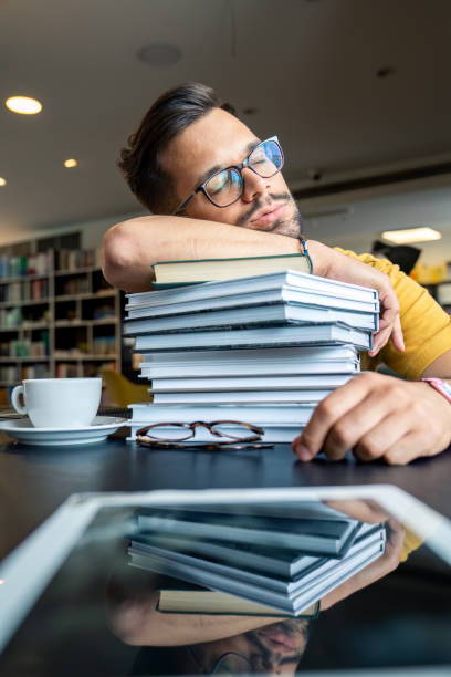 istock Pensive Student in a Library with Books and Coffee 2165842636