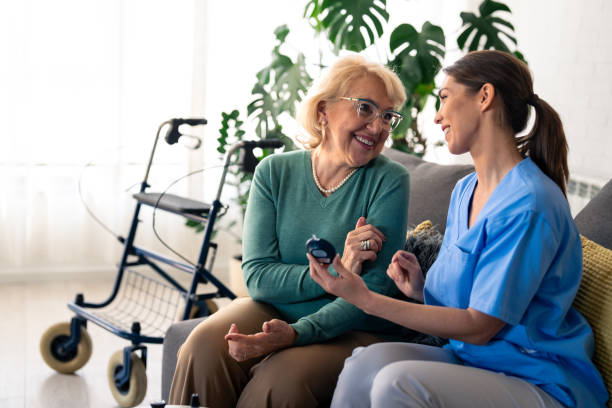 istock Caring Nurse Performs Blood Sugar Check for Senior Lady at Home 2165842902