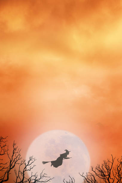 A flying witch is silhouetted against a full moon and an orange Halloween sky.