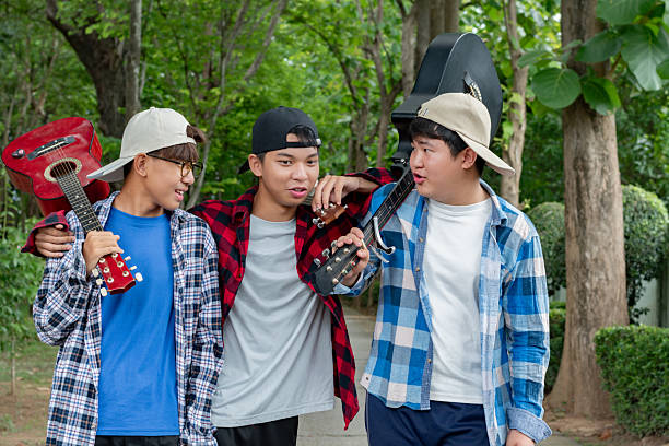 Young asian boys walking along way in public park together, soft and selective focus, concept for teen lifestyle and teenagers's spending times.