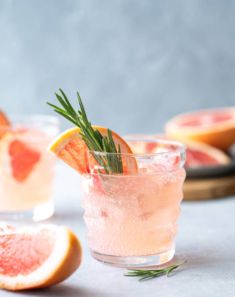 istock Two glasses grapefruit lemonade drink with rosemary and ice on a blue background with fresh citrus slices close up. 2165855019