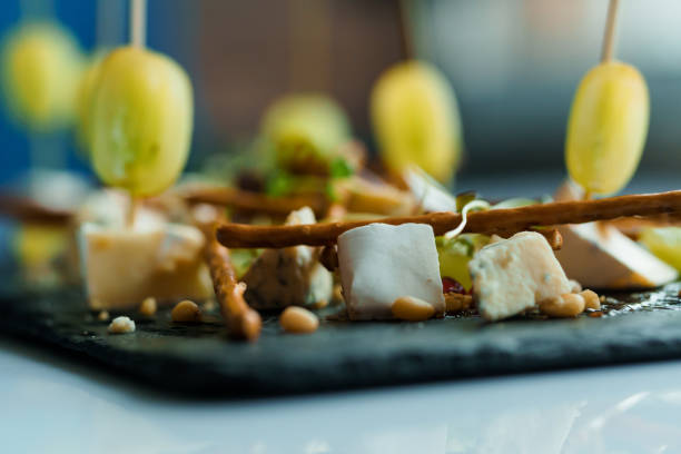 Slicing different types of cheese and grapes. Appetizer with cheese and grapes on a black board on a white background