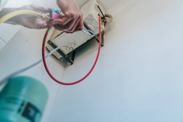 istock Technician working on air conditioner maintenance, refilling freon. Close-up of hands connecting hoses to outdoor unit. HVAC repair and service in summer. Professional cooling system check and maintenance 2165857827