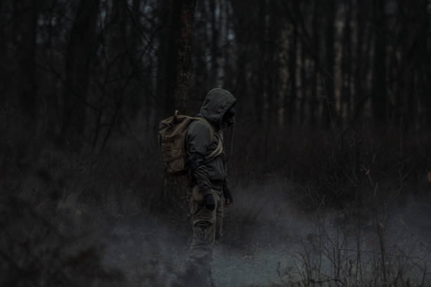 istock A man in camouflage in a post-apocalyptic, smoky, dark forest. Front view. 2165869123