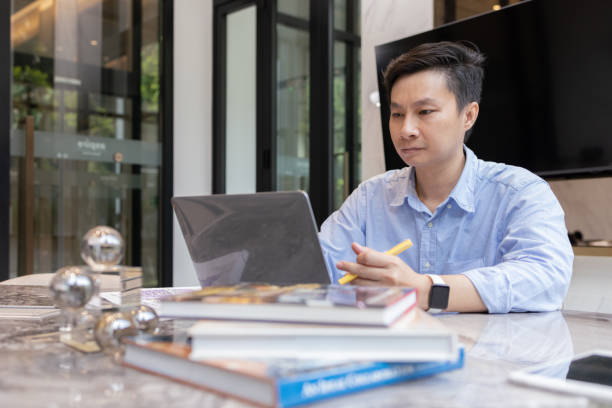 istock Smiling Man Working on Laptop at Desk 2165873489