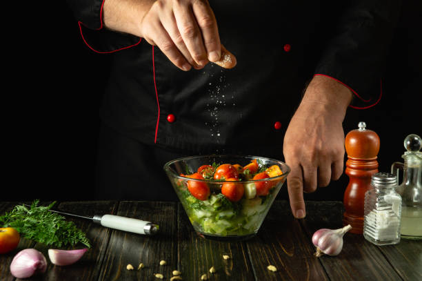 istock A cook at the kitchen table prepares a vegetable mixture for dinner. The chef adds salt to a vegetable salad with his hands. Vegetable diet menu for a restaurant or hotel 2165874255