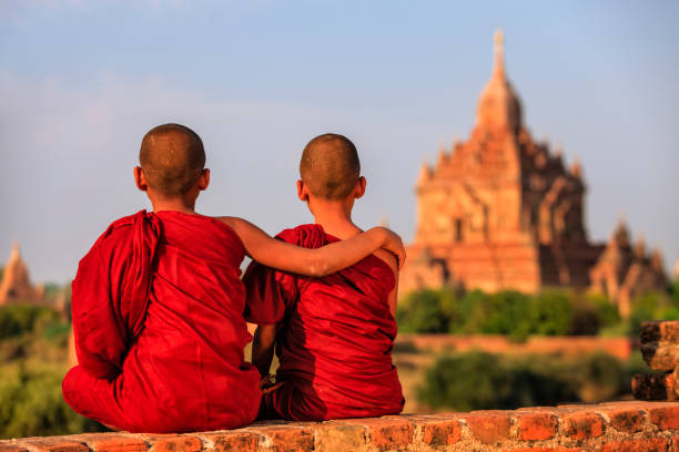 Young Buddhist monks sitting on the temple and looking at the view of ancient Bagan, Myanmar (Burma)
