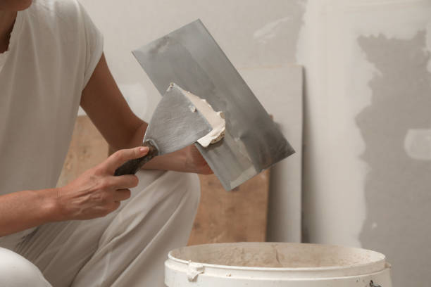 istock Woman taping and mudding joins pieces of drywall into a single solid wall. Fixing dry wall surface and preparation for painting. DIY housing improvement project. 2165878562