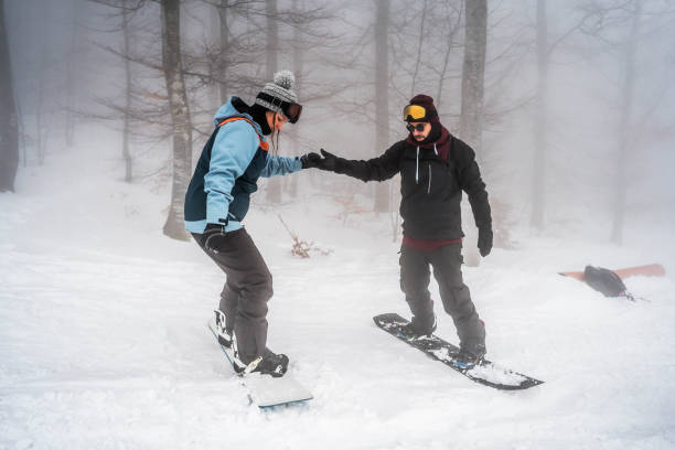istock Couple snowboarding down the slope on a snowy mountain 2165878651