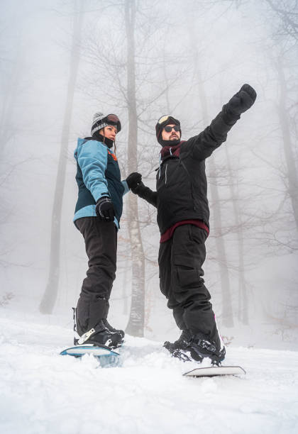 istock Couple snowboarding down the slope on a snowy mountain 2165878714