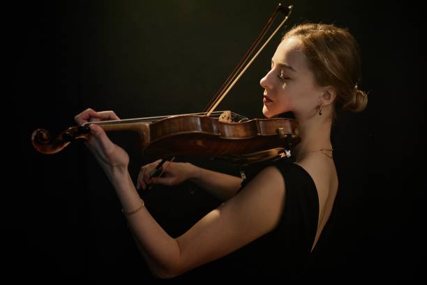 istock Female Violinist Dramatically Playing Classical Music under Top Light 2165879025
