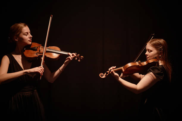 Two Violin Artists Performing Concerto on Black Background