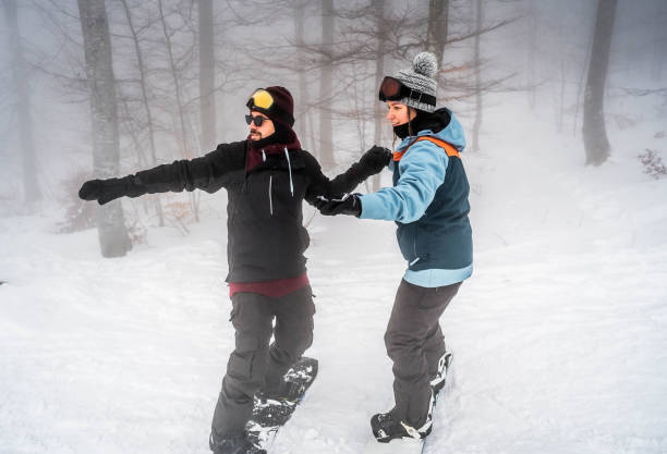 istock Couple snowboarding down the slope on a snowy mountain 2165879311