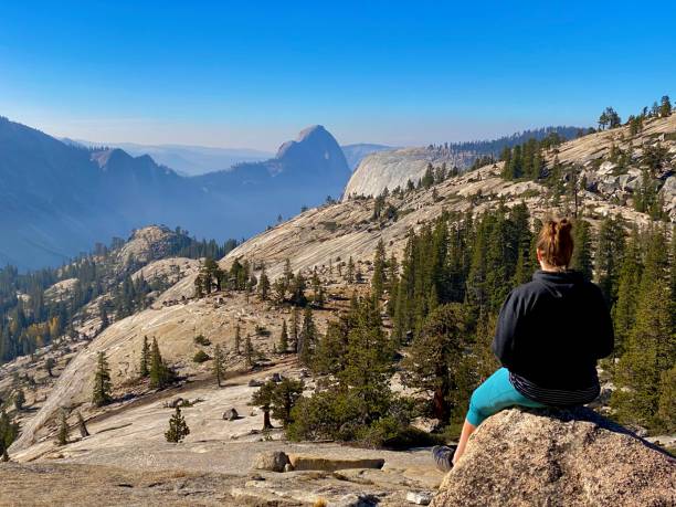 Solo female hiker overlooking valley at Yosemite national park with half dome