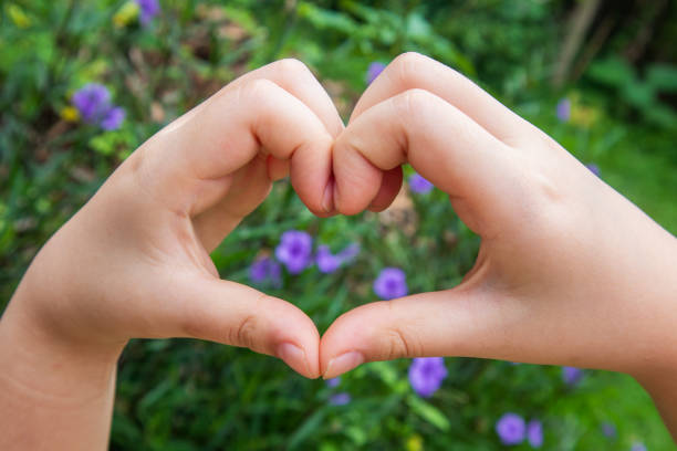 A child's hand making a heart shape shows love and gentle warmth.