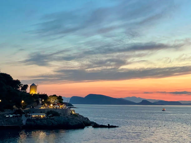 Cliffside restaurants illuminated at sunset in Hydra, Greece