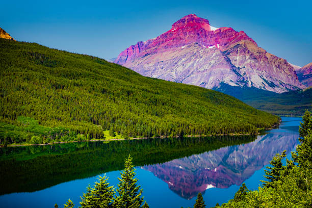 Landscape image of a colorful mountain being reflected in a lake in Glacier National Park