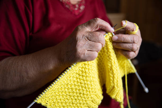 istock Knitting in Progress: Elderly Woman Making Yellow Fabric 2165898727