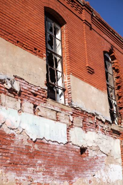 istock Vertical close-up of a broken window on an old red brick building with a clear blue sky 2165899866