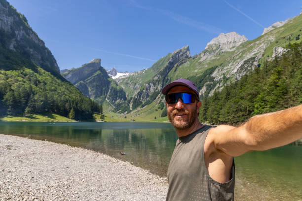 istock Man Taking Selfie by Mountain Lake on Sunny Day 2165901333